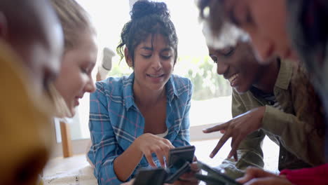 Happy-diverse-group-of-teenage-friends-using-smartphones-and-lying-on-carpet-at-home,-slow-motion