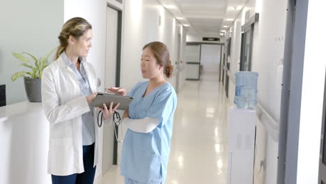 Diverse-female-doctors-using-tablet-discussing-at-hospital-reception,-copy-space,-slow-motion