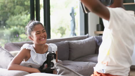 Happy-african-american-brother-and-sister-with-vr-headsets-playing-on-sofa,-copy-space,-slow-motion