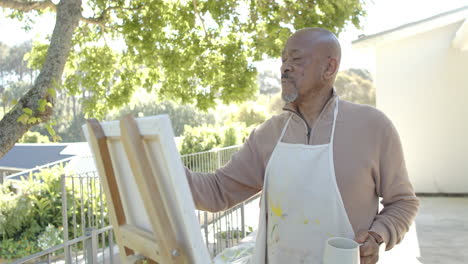 Feliz-Hombre-Birracial-Mayor-Pintando-En-El-Balcón-De-Casa,-Cámara-Lenta