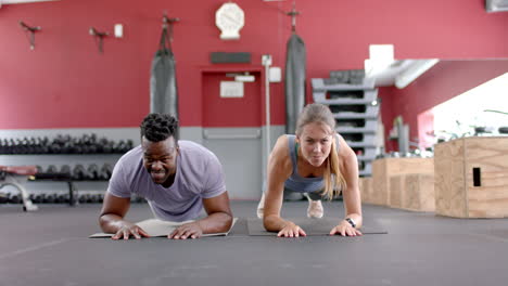 Colocar-Pareja-Diversa-Haciendo-Planchas-En-El-Gimnasio.