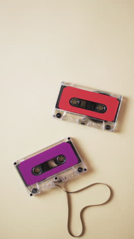 Vertical-video-of-retro-tapes-with-pink-and-red-labels-and-copy-space-on-yellow-background