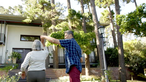 Happy-biracial-senior-couple-dancing-in-sunny-garden