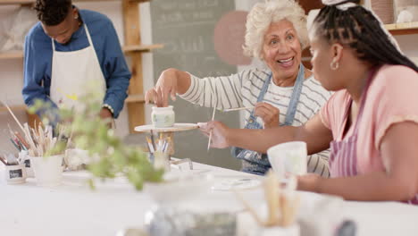 Two-diverse-female-potters-working-on-clay-vase-and-smiling-in-pottery-studio,-slow-motion