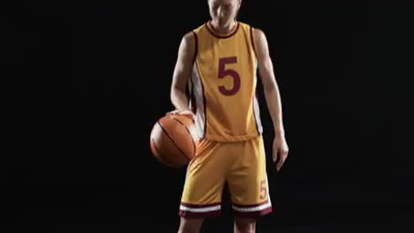 Young-Caucasian-woman-in-basketball-attire-poses-confidently-on-a-black-background