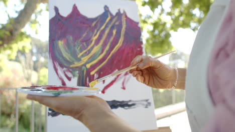 Mujer-Birracial-Mayor-Pintando-Con-Paleta-De-Pintura-En-El-Balcón-De-Casa,-Cámara-Lenta