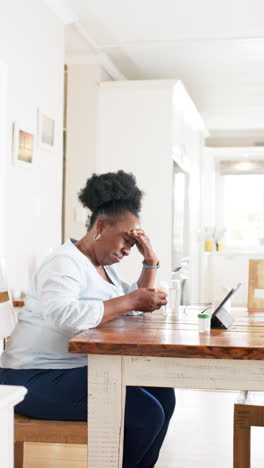 African-american-senior-woman-having-video-call-and-holding-medicines-in-sunny-room,-slow-motion