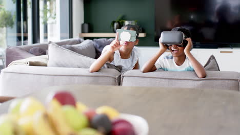 Happy-african-american-brother-and-sister-in-vr-headsets-on-sofa,-copy-space,-slow-motion