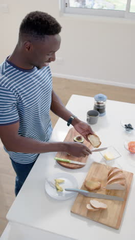 Hombre-Afroamericano-Preparando-Tostadas-En-Una-Cocina-Soleada,-Cámara-Lenta