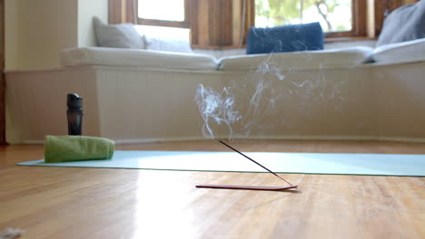 Incense-sticks-with-smoke-trails-on-floor-over-yoga-mat-at-home