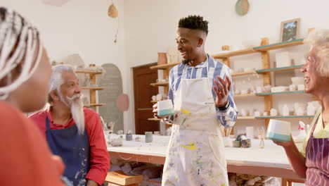 Happy-diverse-group-of-potters-discussing-and-laughing-in-pottery-studio