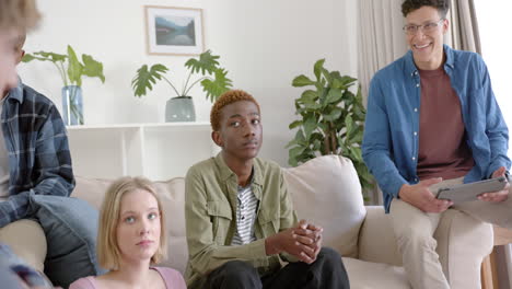 Thoughtful-diverse-group-of-teenage-friends-at-meeting-talking-and-using-tablet-at-home,-slow-motion