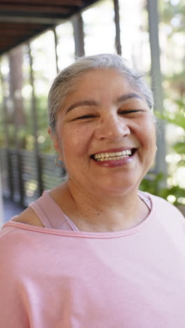 Portrait-of-happy-biracial-senior-woman-in-sunny-outdoors,-vertical