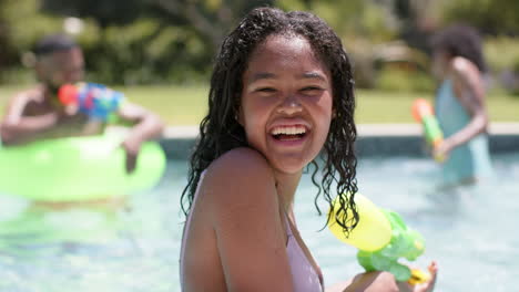 Retrato-De-Una-Feliz-Hija-Afroamericana-Jugando-Con-Su-Familia-En-Una-Piscina-Soleada,-Cámara-Lenta