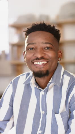 Happy-african-american-man-with-beard-sitting-and-smiling-in-pottery-studio,-slow-motion