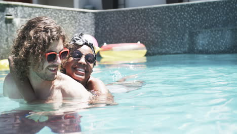 Diverse-couple,-a-young-Caucasian-man-and-an-African-American-woman,-enjoy-a-sunny-pool-day