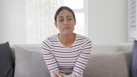 Biracial-woman-sitting-on-sofa-having-video-call,-slow-motion