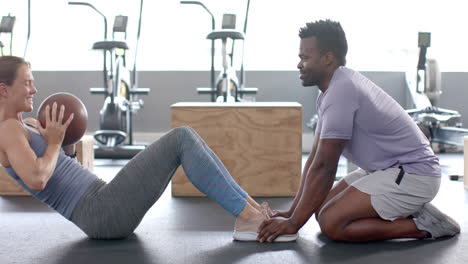 Fit-young-Caucasian-woman-and-African-American-man-exercise-at-the-gym-with-a-medicine-ball