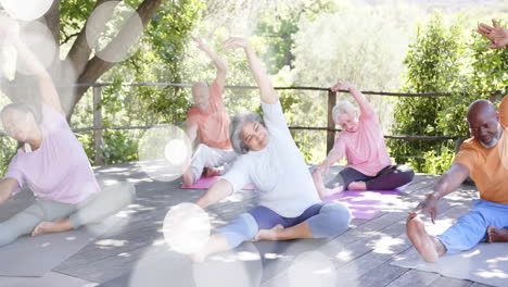 Animation-of-spots-of-light-and-trees-over-diverse-senior-people-practicing-yoga-in-garden