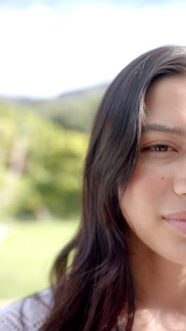 Vertical-video-half-portrait-of-happy-biracial-teenage-girl-in-sunny-garden,-copy-space,-slow-motion