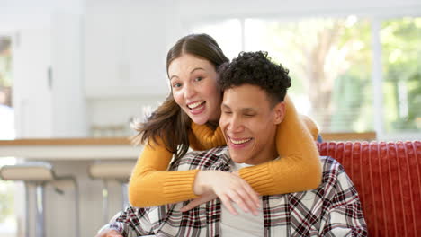 Retrato-De-Una-Feliz-Pareja-Diversa-Sentada-En-Un-Sofá-Y-Abrazándose-En-Casa,-En-Cámara-Lenta