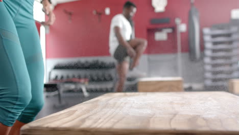 Fit-young-Caucasian-woman-and-African-American-man-at-the-gym-doing-box-jumps