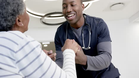 Feliz-Médico-Afroamericano-Cogido-De-La-Mano-De-Una-Mujer-Mayor-En-El-Hospital,-Cámara-Lenta