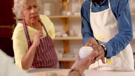 Focused-diverse-group-of-potters-discussing-about-work-in-pottery-studio