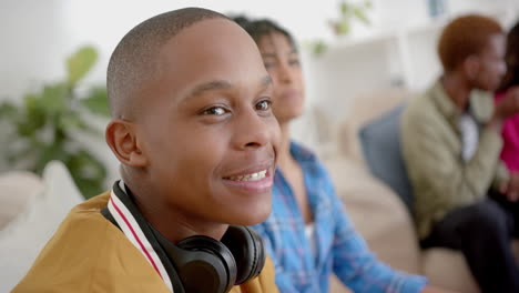 Happy-diverse-group-of-teenage-friends-sitting-on-couch-and-playing-video-games-at-home,-slow-motion