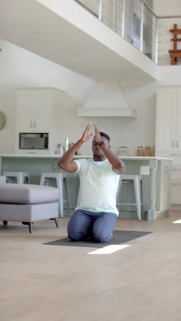 Focused-african-american-man-practising-yoga-meditation-in-sunny-living-room,-slow-motion