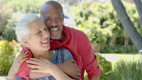 Retrato-De-Una-Feliz-Pareja-Birracial-Mayor-Abrazándose-En-Un-Soleado-Jardín-En-Casa,-Cámara-Lenta