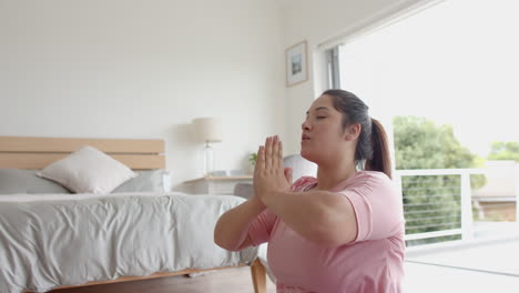 Plus-size-biracial-woman-sitting-on-floor-practicing-yoga-meditation,-copy-space,-slow-motion