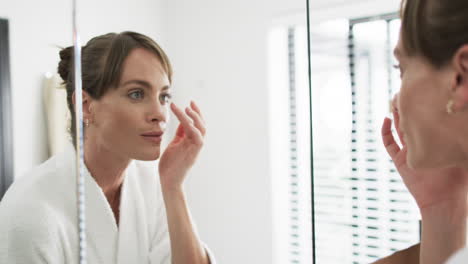 Middle-aged-Caucasian-woman-examines-her-skin-in-a-mirror-at-home