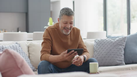 Feliz-Hombre-Birracial-Mayor-Que-Tiene-Videollamada-Con-Teléfono-Inteligente-En-El-Sofá-En-Una-Sala-De-Estar-Soleada,-Cámara-Lenta