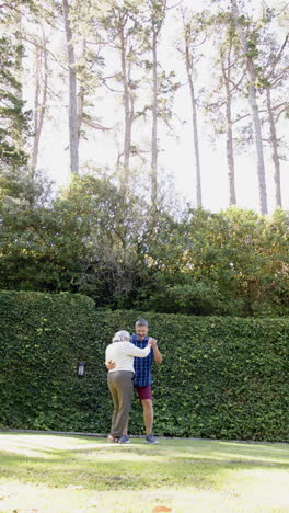 Feliz-Pareja-De-Ancianos-Birraciales-Bailando-En-Un-Jardín-Soleado,-Vertical