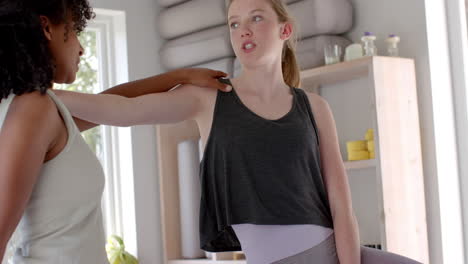 Focused-diverse-fitness-women-exercising-together-on-mat-in-white-room,-slow-motion