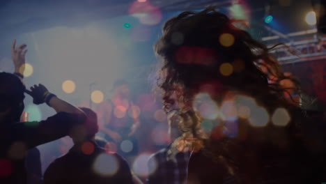 Happy-diverse-people-dancing-and-raising-hands-during-concert-over-light-spots-and-cityscape