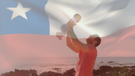 Animación-De-La-Bandera-Chilena-Sobre-Un-Padre-Caucásico-Sosteniendo-A-Un-Bebé-En-La-Playa.