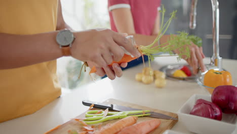 Pareja-Diversa-Preparando-Y-Lavando-Verduras-Frescas-En-La-Cocina,-Cámara-Lenta