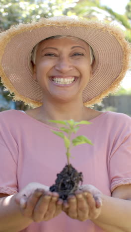 Vídeo-Vertical-De-Retrato-De-Una-Feliz-Mujer-Birracial-Mayor-Trabajando-En-El-Jardín,-Cámara-Lenta