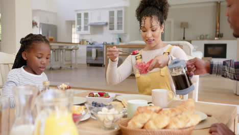 Happy-african-american-parents-and-daughter-having-breakfast-at-home,-slow-motion