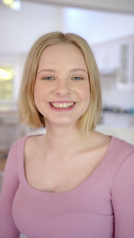 Vertical-video-of-portrait-of-caucasian-female-teenager-with-blond-hair-at-home,-slow-motion