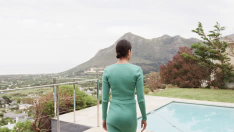 Portrait-of-happy-biracial-woman-walking-on-terrace-at-home,-slow-motion