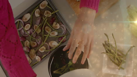 Biracial-woman-arranging-chopped-vegetables-in-kitchen,-cooking-over-spots-of-light