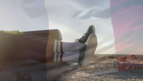 Animation-of-flag-of-france-over-legs-of-african-american-man-lying-on-pick-up-truck-at-beach