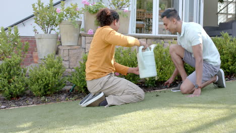 Feliz-Pareja-Gay-Diversa-Haciendo-Jardinería-Arrodillada-En-Un-Jardín-Soleado,-Espacio-Para-Copiar,-Cámara-Lenta