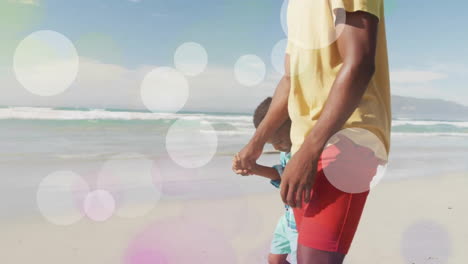 Animación-De-Puntos-De-Luz-Sobre-Un-Feliz-Padre-E-Hijo-Afroamericanos-Caminando-Por-La-Playa