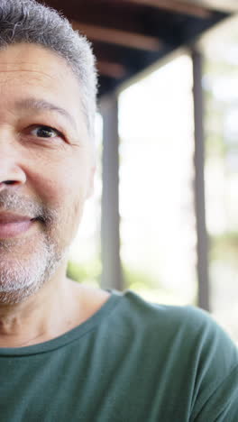 Portrait-of-happy-biracial-senior-man-in-sunny-outdoors,-vertical