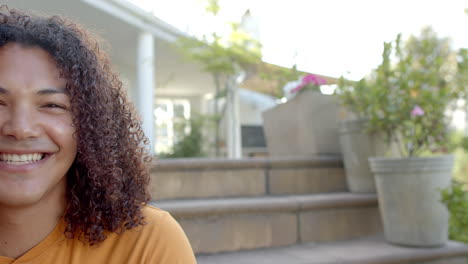 Half-portrait-of-happy-biracial-man-with-long-hair-smiling-in-sunny-garden,-slow-motion,-copy-space