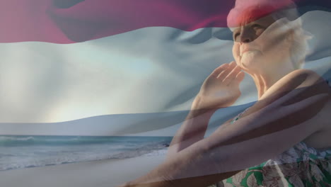 Animación-De-La-Bandera-De-Los-Países-Bajos-Sobre-Una-Mujer-Caucásica-Mayor-En-La-Playa.